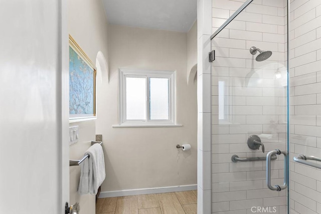 bathroom featuring baseboards, wood finished floors, and a stall shower