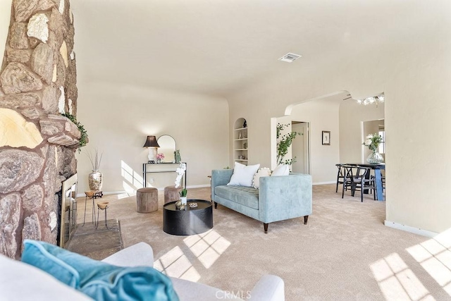 living area with visible vents, built in shelves, baseboards, carpet, and arched walkways