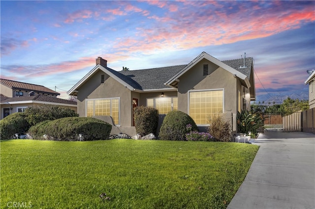 ranch-style house with stucco siding, a chimney, and a front yard