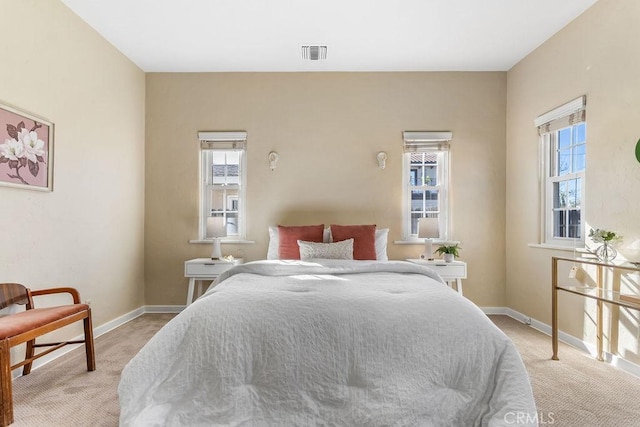 bedroom featuring visible vents, light carpet, and baseboards