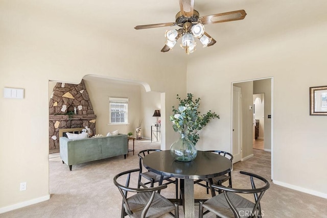 dining space featuring baseboards, light colored carpet, and ceiling fan