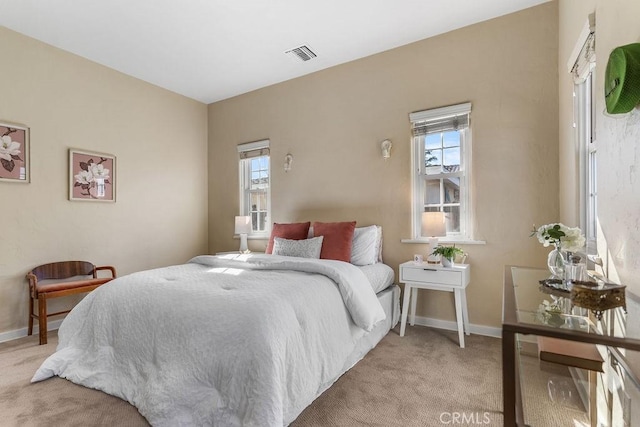 bedroom featuring light carpet, visible vents, multiple windows, and baseboards