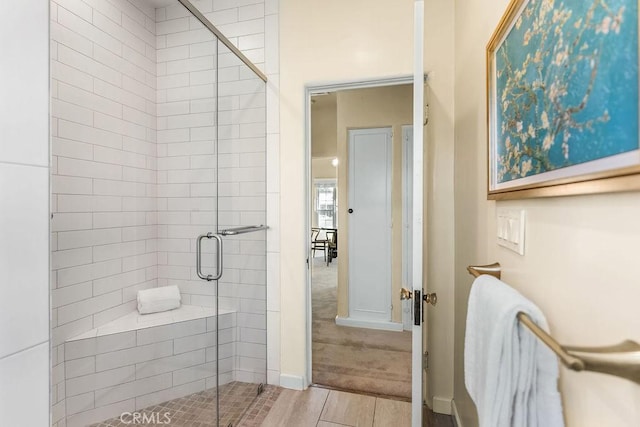 bathroom with a shower stall and baseboards