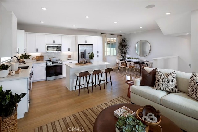 kitchen with open floor plan, a breakfast bar, light wood-type flooring, stainless steel appliances, and a sink