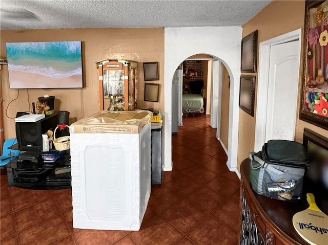 interior space featuring arched walkways, a textured ceiling, and dark tile patterned flooring