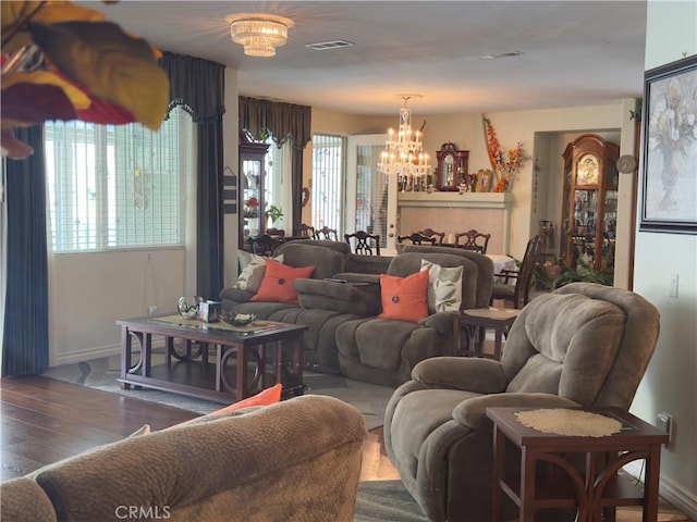 living area featuring an inviting chandelier, baseboards, wood finished floors, and a wealth of natural light
