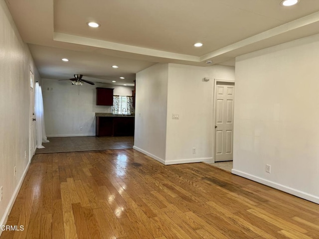 spare room featuring recessed lighting, baseboards, a raised ceiling, and hardwood / wood-style floors