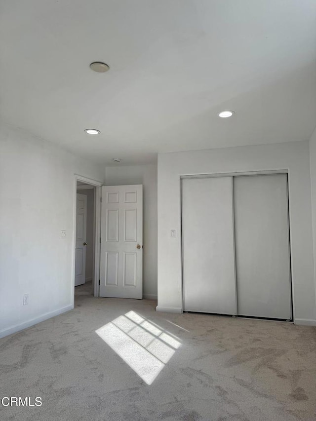 unfurnished bedroom featuring recessed lighting, carpet flooring, baseboards, and a closet