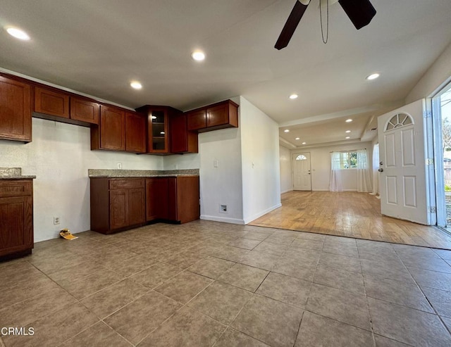 kitchen with light stone counters, glass insert cabinets, ceiling fan, and recessed lighting