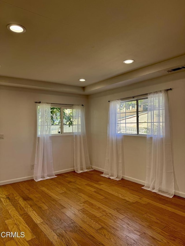 spare room with light wood finished floors, plenty of natural light, recessed lighting, and visible vents