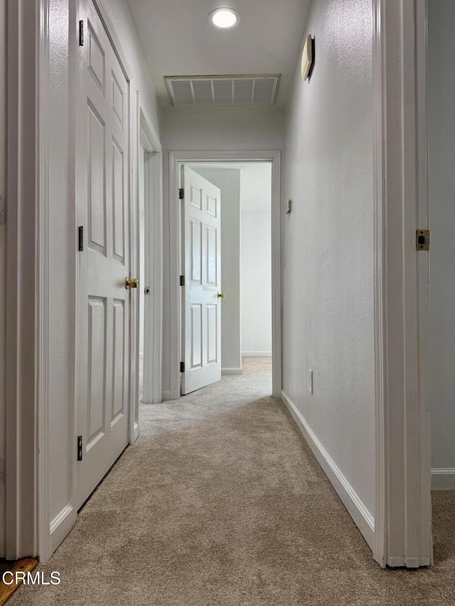 hallway featuring visible vents, baseboards, carpet flooring, and a textured wall