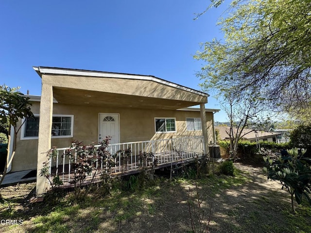 rear view of property with central AC unit and stucco siding