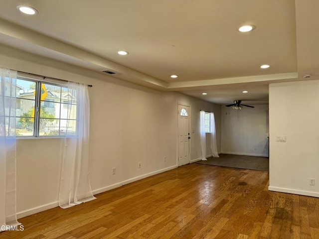 spare room with a ceiling fan, wood finished floors, visible vents, recessed lighting, and a raised ceiling