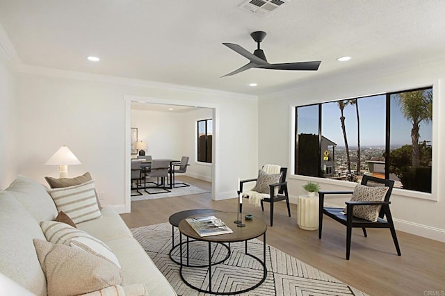 living area with visible vents, recessed lighting, light wood-style floors, crown molding, and ceiling fan