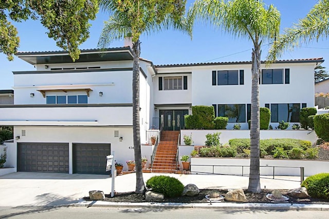 view of front of home featuring stucco siding, driveway, stairs, and a garage