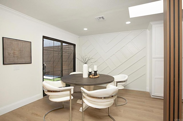 dining room with visible vents, light wood-style flooring, a skylight, and baseboards