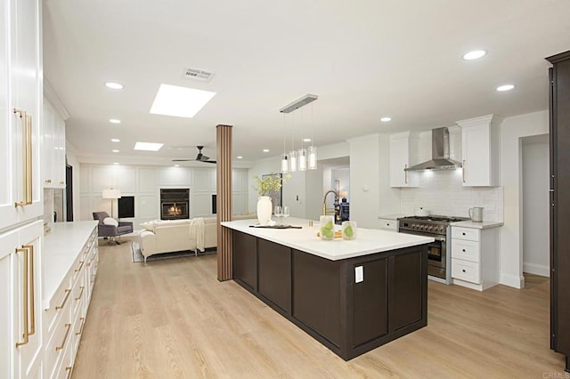 kitchen featuring visible vents, wall chimney exhaust hood, light countertops, and high end stainless steel range