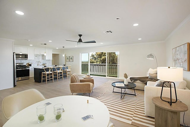 living area with recessed lighting, visible vents, a ceiling fan, and crown molding