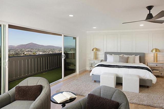 bedroom featuring access to exterior, recessed lighting, wood finished floors, a decorative wall, and a mountain view