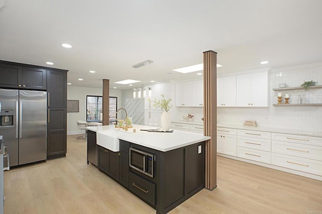 kitchen featuring light wood-style flooring, appliances with stainless steel finishes, light countertops, and a sink