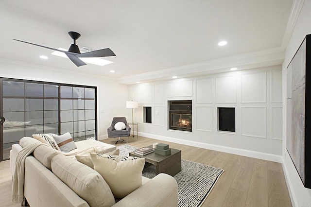 living room with a decorative wall, light wood-style flooring, and crown molding