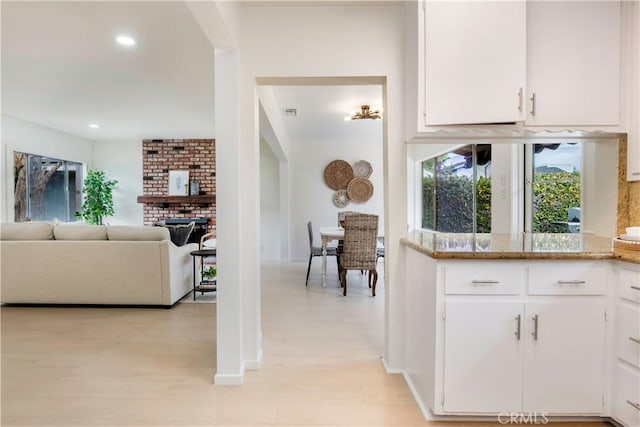 kitchen with light stone counters, light wood-style flooring, recessed lighting, and white cabinetry