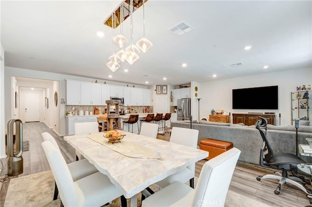 dining space featuring an inviting chandelier, light wood-style flooring, recessed lighting, and visible vents