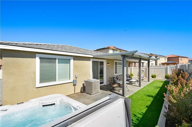 back of property featuring stucco siding, a fenced backyard, an outdoor hot tub, and a patio area