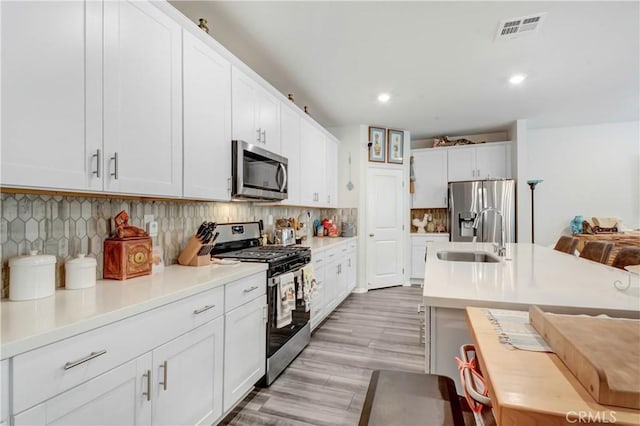 kitchen featuring visible vents, a sink, tasteful backsplash, appliances with stainless steel finishes, and light countertops