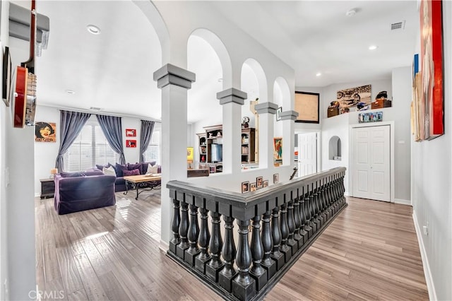 corridor featuring recessed lighting, light wood finished floors, visible vents, baseboards, and decorative columns