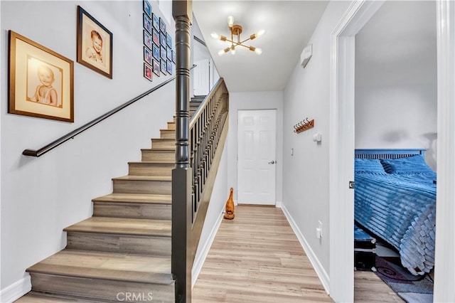 staircase with baseboards, a notable chandelier, and wood finished floors