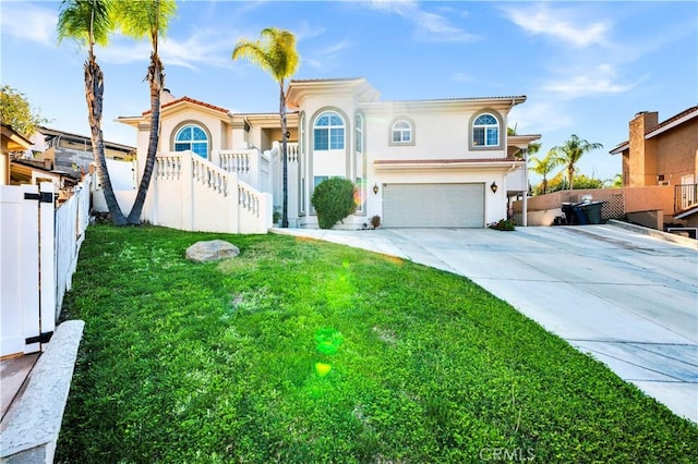 mediterranean / spanish house featuring a garage, concrete driveway, fence, a front yard, and stucco siding