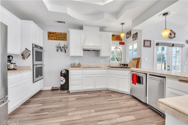 kitchen with appliances with stainless steel finishes, light wood-style flooring, decorative light fixtures, white cabinetry, and visible vents