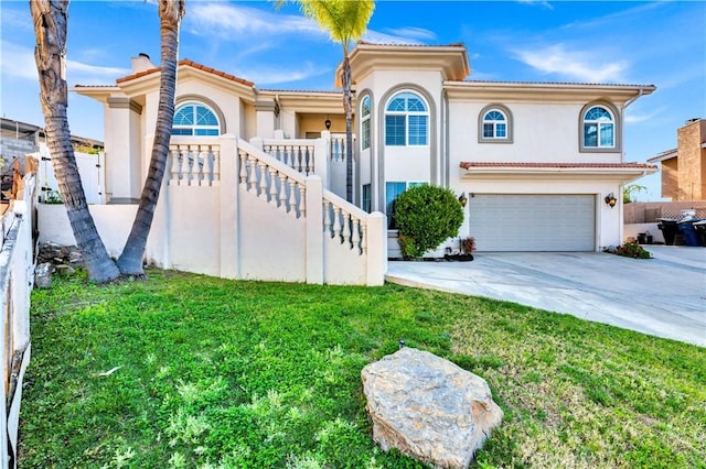 mediterranean / spanish-style home with fence, stucco siding, concrete driveway, a front yard, and a garage