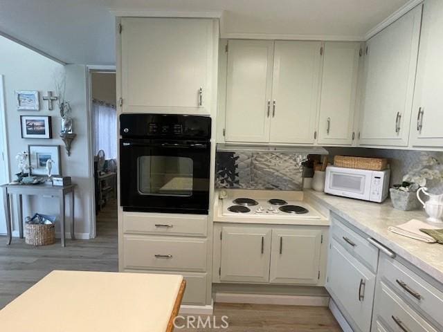 kitchen with backsplash, white cabinetry, white appliances, light wood finished floors, and light countertops