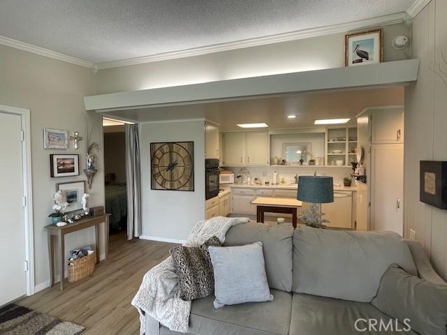 living room featuring wood finished floors, a textured ceiling, and ornamental molding