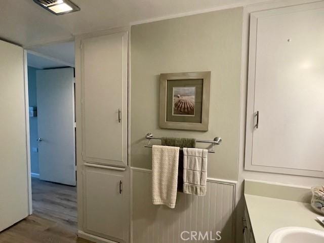 bathroom featuring visible vents, vanity, a wainscoted wall, and wood finished floors