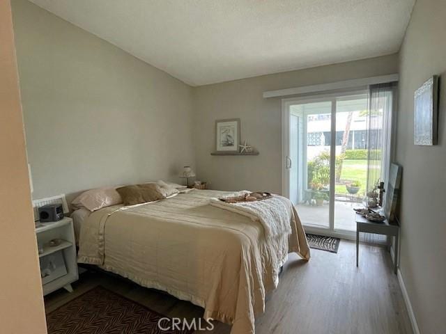 bedroom with access to exterior, wood finished floors, and baseboards