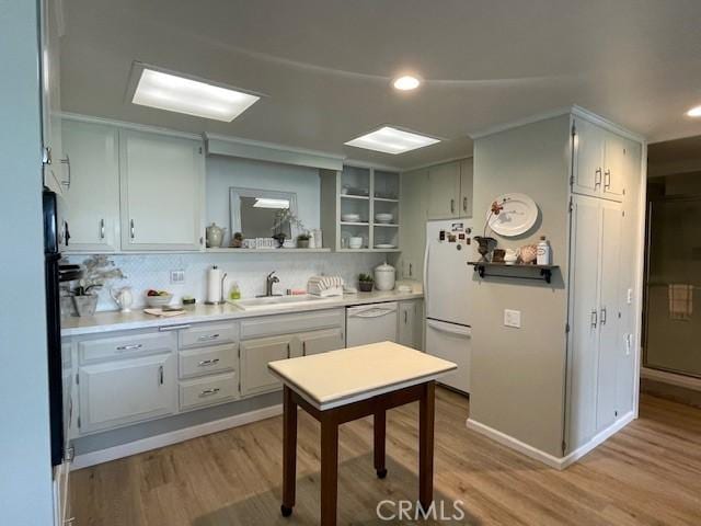 kitchen with light wood finished floors, a sink, light countertops, white appliances, and open shelves