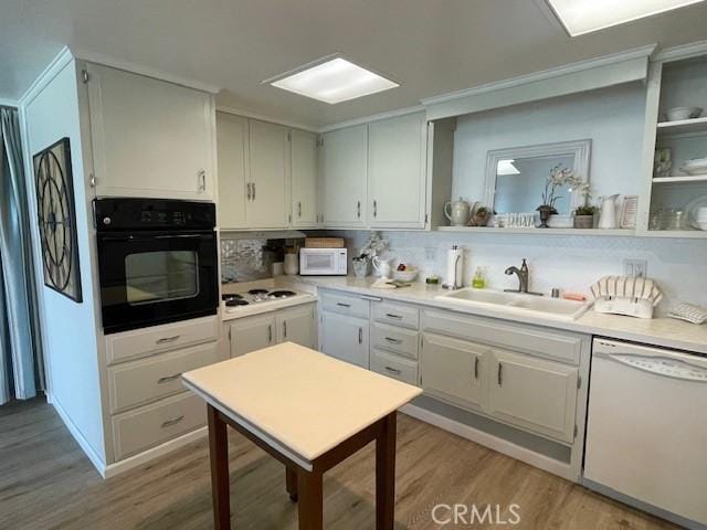 kitchen featuring white appliances, light countertops, light wood-type flooring, and a sink