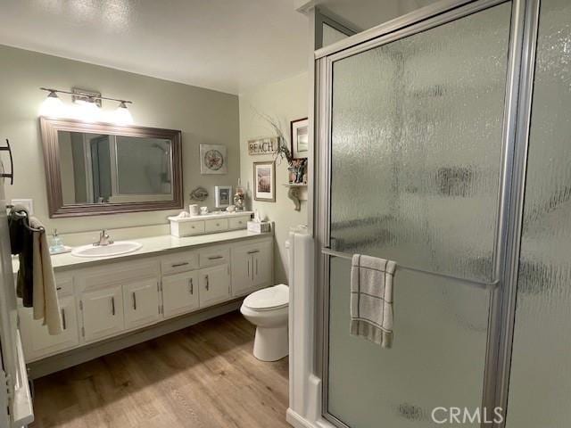 full bathroom with vanity, wood finished floors, a shower stall, and toilet