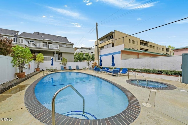 community pool with a patio area, a fenced backyard, and a hot tub