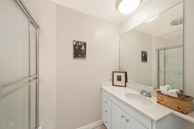 bathroom featuring vanity, baseboards, and a tile shower