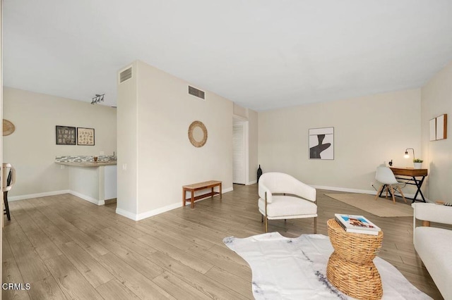 living room with visible vents, light wood-type flooring, and baseboards