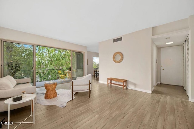 living room with light wood-style flooring, baseboards, and visible vents