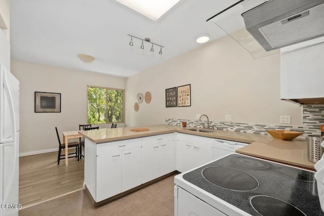 kitchen with white appliances, a peninsula, a sink, white cabinets, and tasteful backsplash