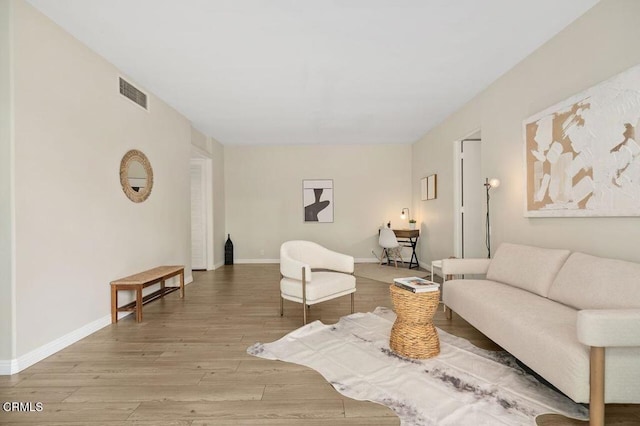 living room featuring light wood-style flooring, baseboards, and visible vents