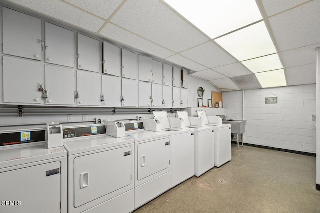 laundry room with washer and dryer, concrete block wall, and cabinet space