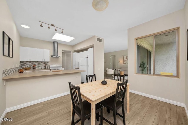 dining space featuring light wood-style flooring and baseboards