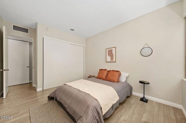 bedroom with visible vents, baseboards, a closet, and light wood-style flooring